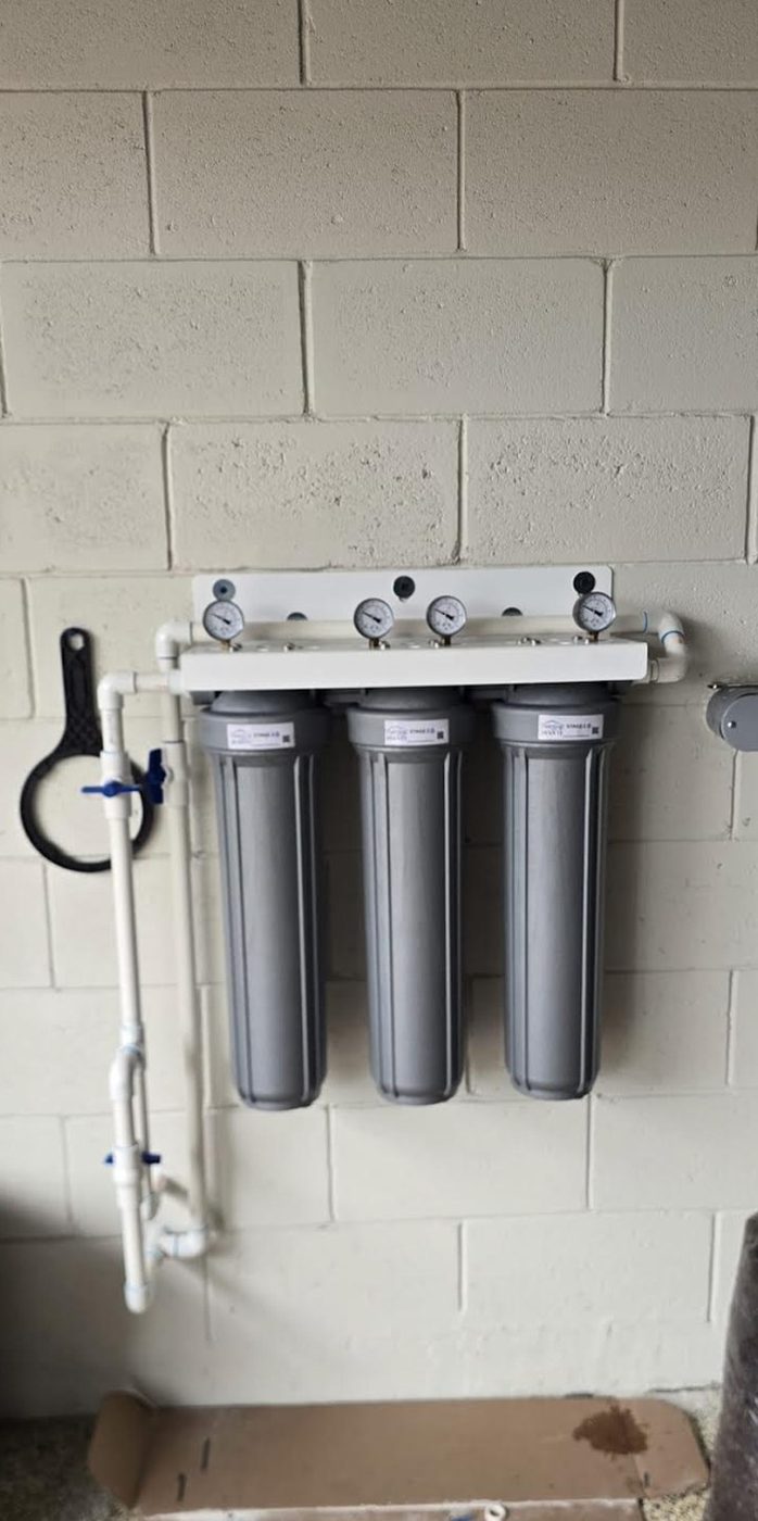 A three-stage AVANTI whole-home water filtration system installed on a garage wall