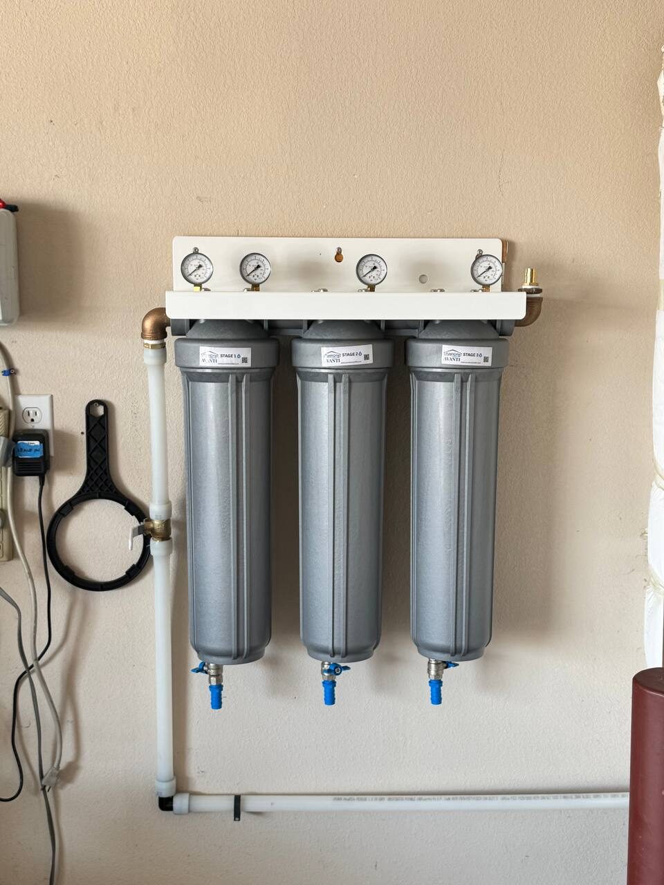 A three-stage AVANTI filtration system with pressure gauges mounted on a wall