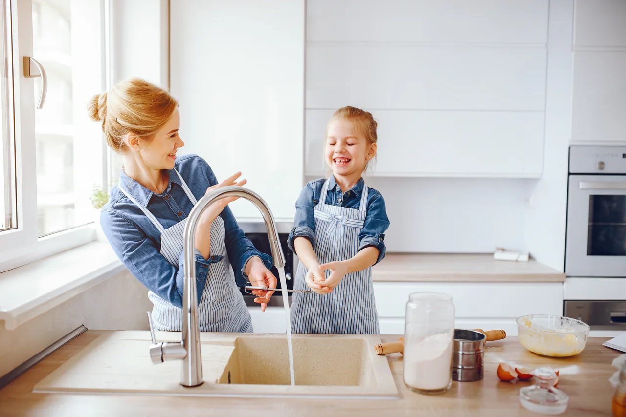 Mother and daughter enjoying fresh water in their kitchen